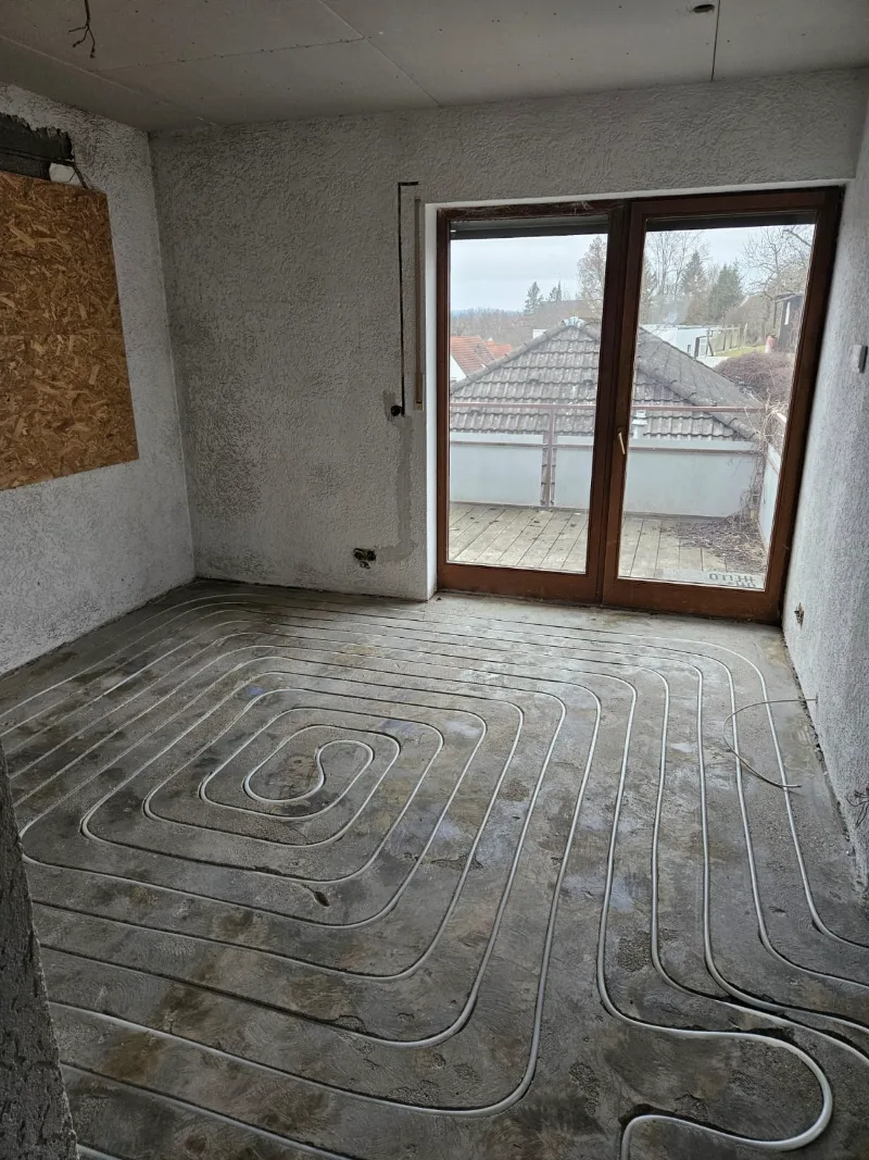 Verlegte Heizrohre führen bis an die Schwelle einer Balkontür.